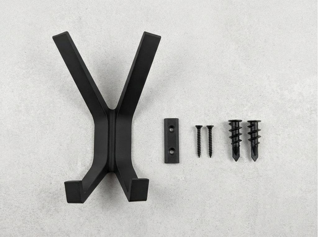 Black Garuda X shaped coat hanger with screws on a gray background.